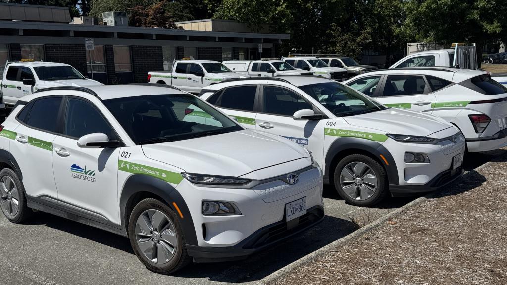 City of Abbotsford electric vehicle fleet featuring white electric SUVs with EV branding parked at a municipal operations facility.