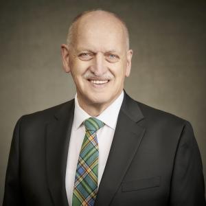 Councillor Dave Loewen, in a dark suit with a white shirt and green patterned tie.