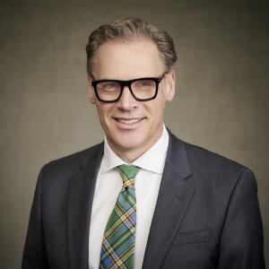 Councillor Mark Warkentin, in a dark suit with a white shirt and green patterned tie.