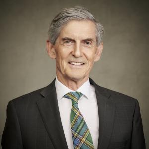 Councillor Simon Gibson, in a dark suit with a white shirt and green patterned tie.