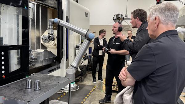 Mayor Siemens watching a robotic arm at work at Tiger Tool.
